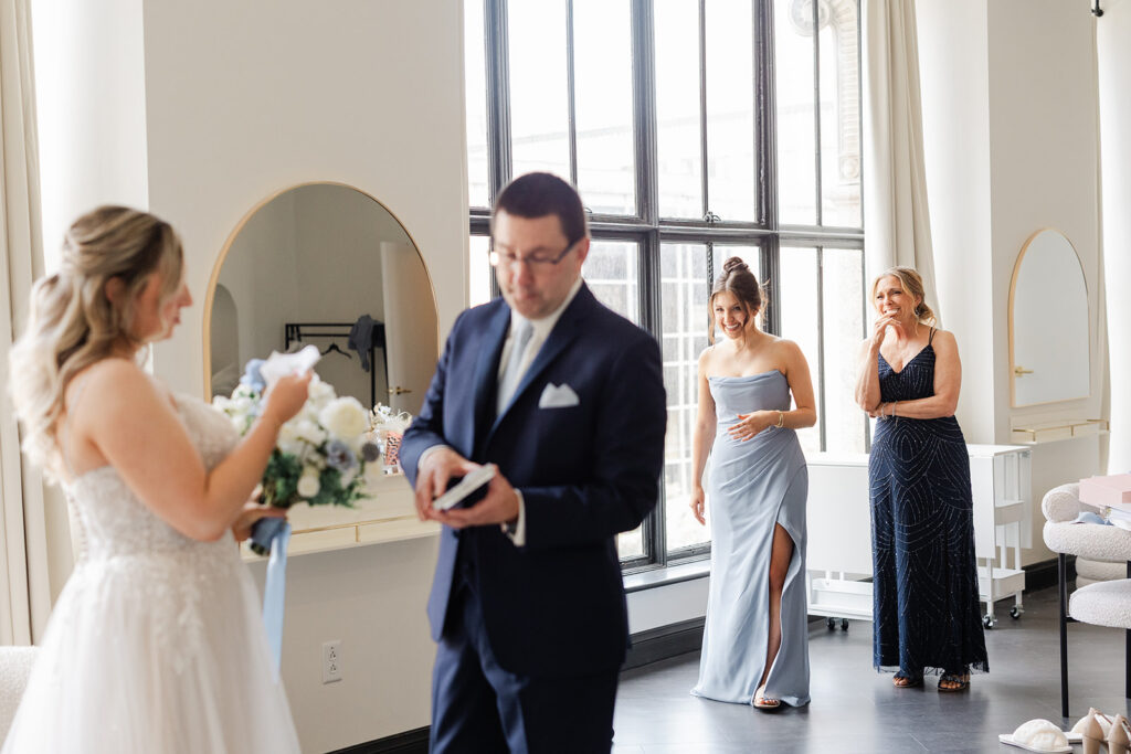 Rochester wedding photographer capturing a documentary moment of a father giving a gift to the bride during a first look.