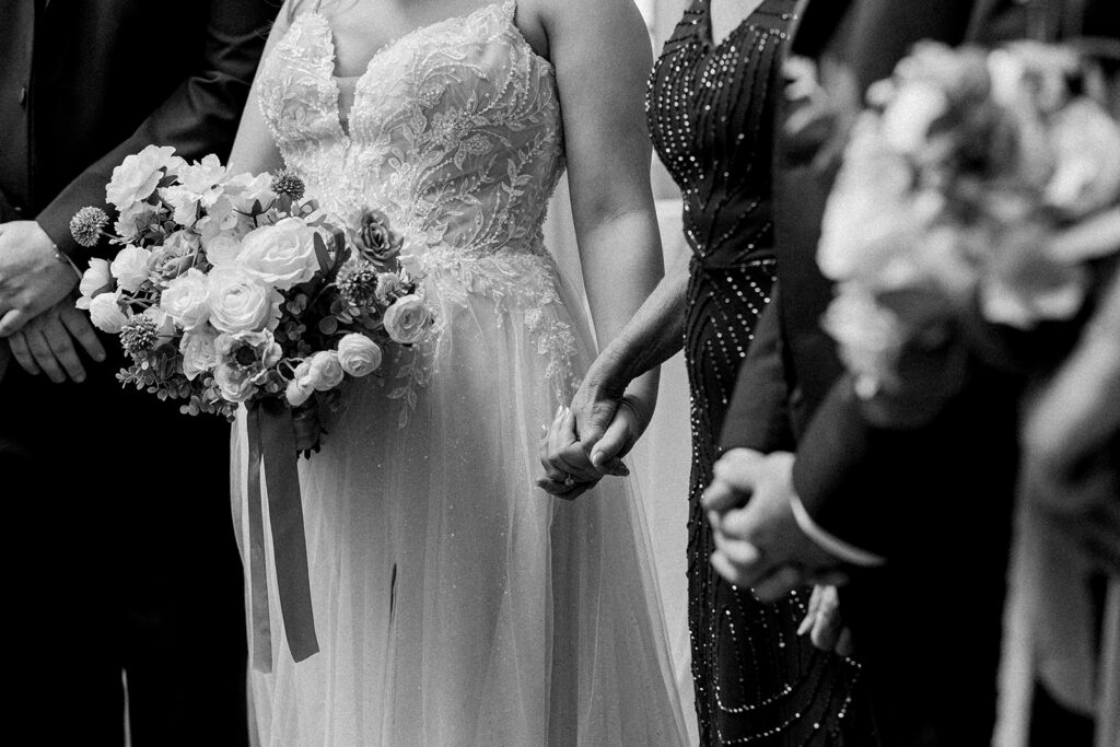 Rochester wedding photographer capturing a black and white documentary moment of a bride and her mother holding hands.